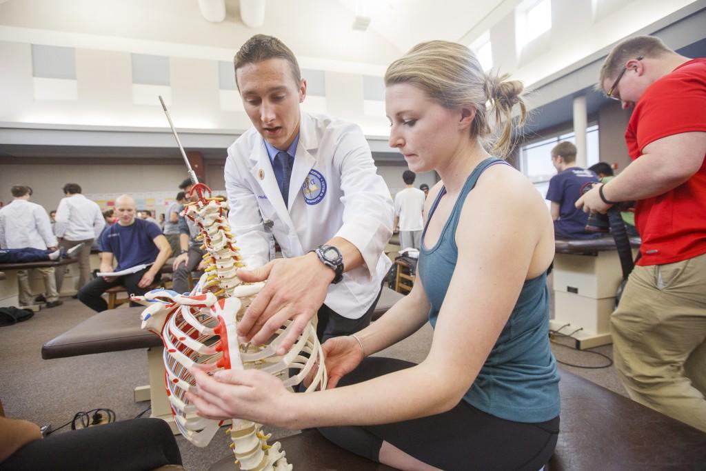 A student reviews a rib cage model with their professor in the O M M lab